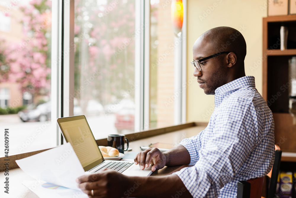 Black man using laptop in coffee shop Black man using laptop in coffee shop