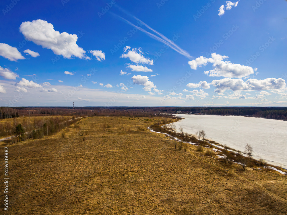 Spring landscape with a bird's eye view of the field and the ice lake with fishermen
