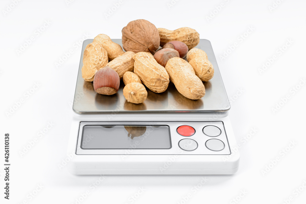 Blend of nuts on electronic scales with white background. Diet and ...