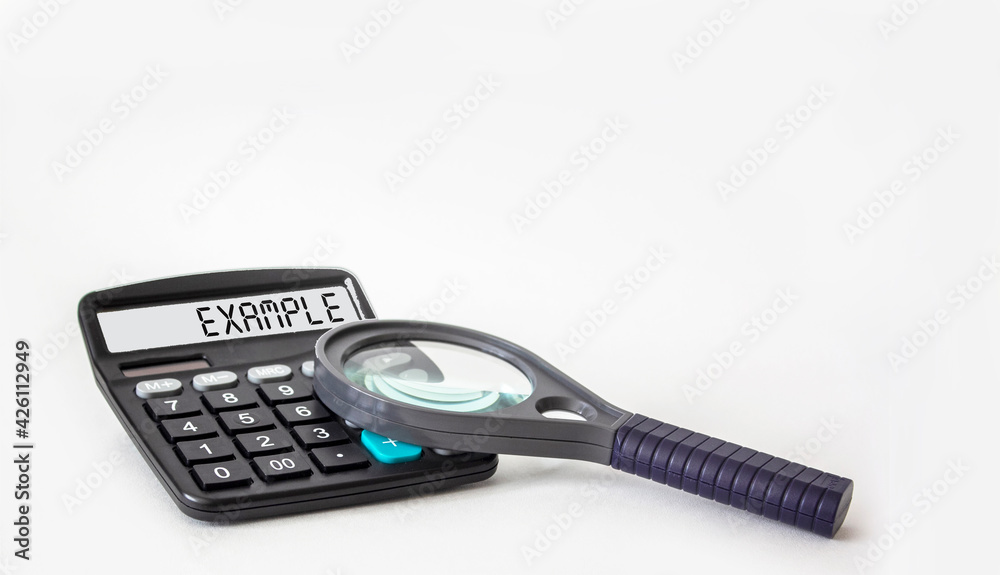 The word EXAMPLE is written on the display of a calculator and on a white background next to a magnifying glass, business concept The word EXAMPLE is written on the display of a calculator and on a white background next to a magnifying glass, business concept