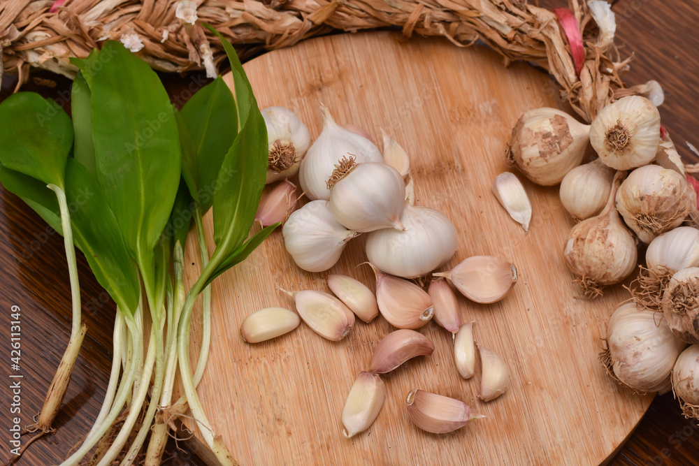 Wild garlic ramson or bear garlic with garlic bulb and garlic cloves on wooden cutting board
Wild garlic ramson or bear garlic with garlic bulb and garlic cloves on wooden cutting board