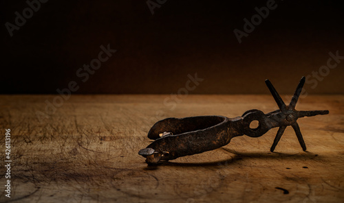Old metal spur on wooden surface