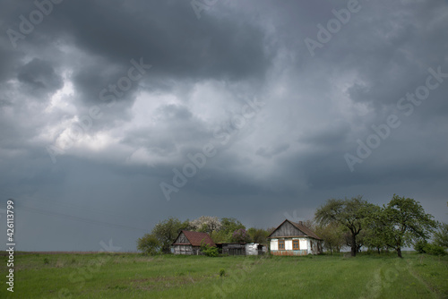 House in the field under storm clouds. Rural landscape.