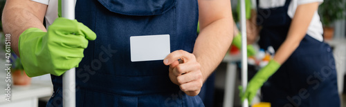 Cropped view of cleaner with mop holding empty card in office  banner