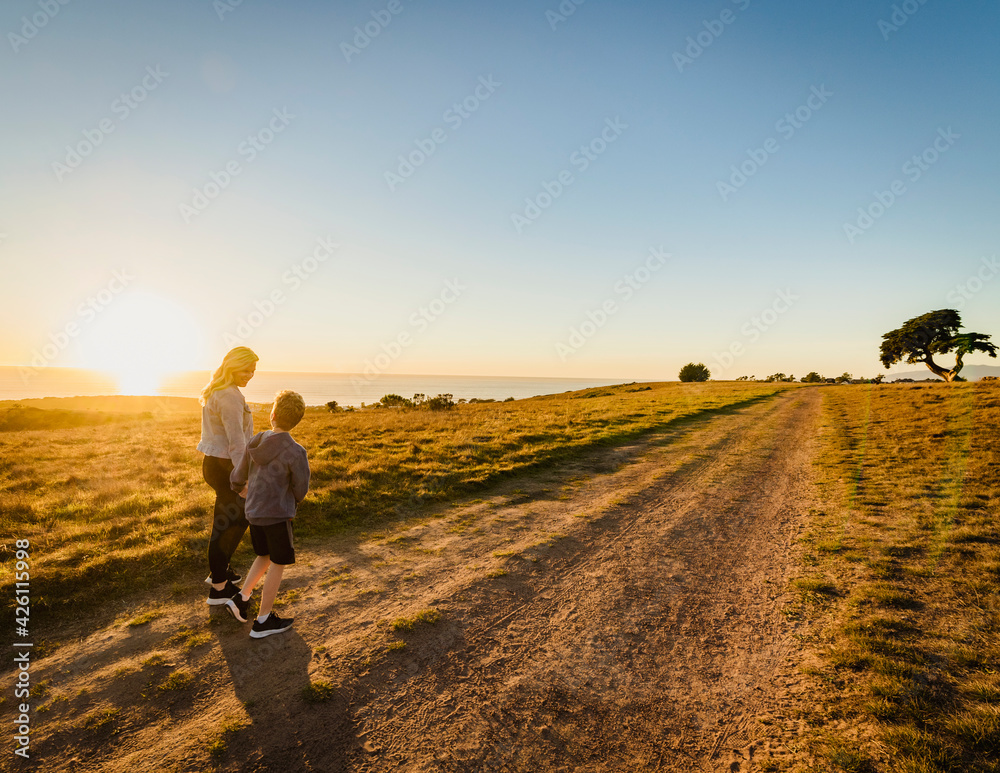 United States, California, Cambria, Rear view of mother and son (10-11) walking in landscape at sunset United States, California, Cambria, Rear view of mother and son (10-11) walking in landscape at sunset