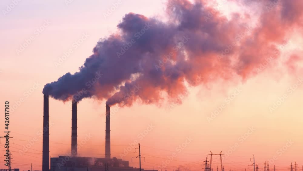 Sunset over the industrial city.Factory chimneys smoke.Environmental problem of environmental and atmospheric pollution.Climate change,environmental disaster.The sky is smoky with toxic substances