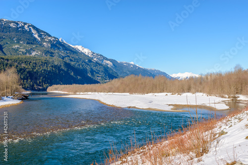 Majestic mountain river in winter over snow mountains and blue sky in Vancouver, Canada.