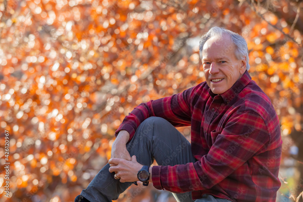 Outdoor portrait of senior man sitting near autumn tree Outdoor portrait of senior man sitting near autumn tree