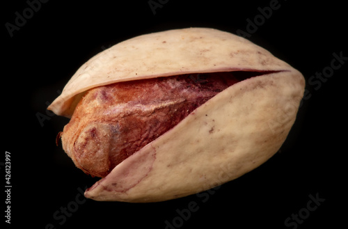 Close-up of fresh pistachio nuts on a black background.