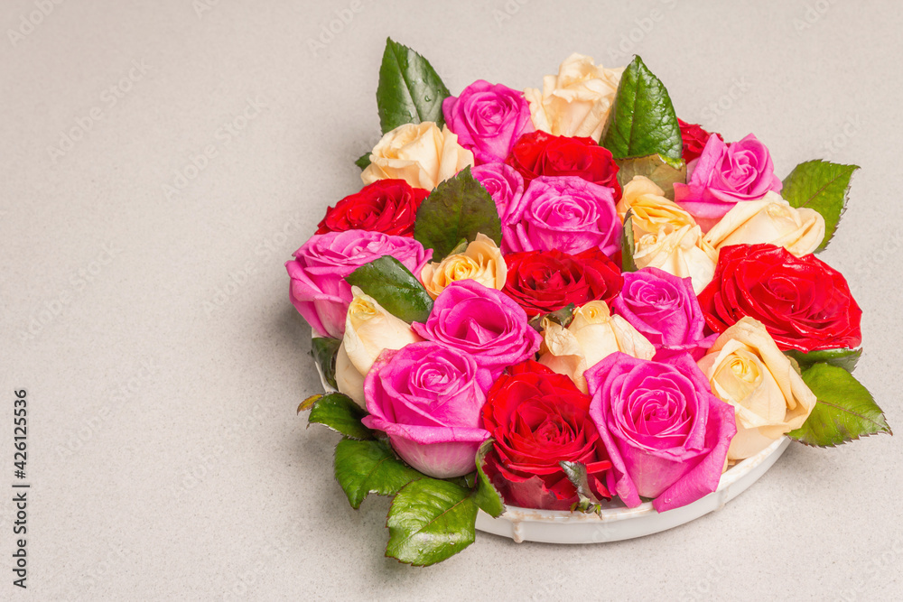 Composition of fresh multicolored roses on ceramic stand