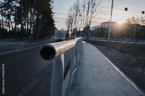 Obraz na plátně Street fence at sunrise, city stream of cars stands in traffic.