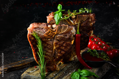Two juicy grilled steaks with spices and herbs on a black background. Top view. Rustic style.