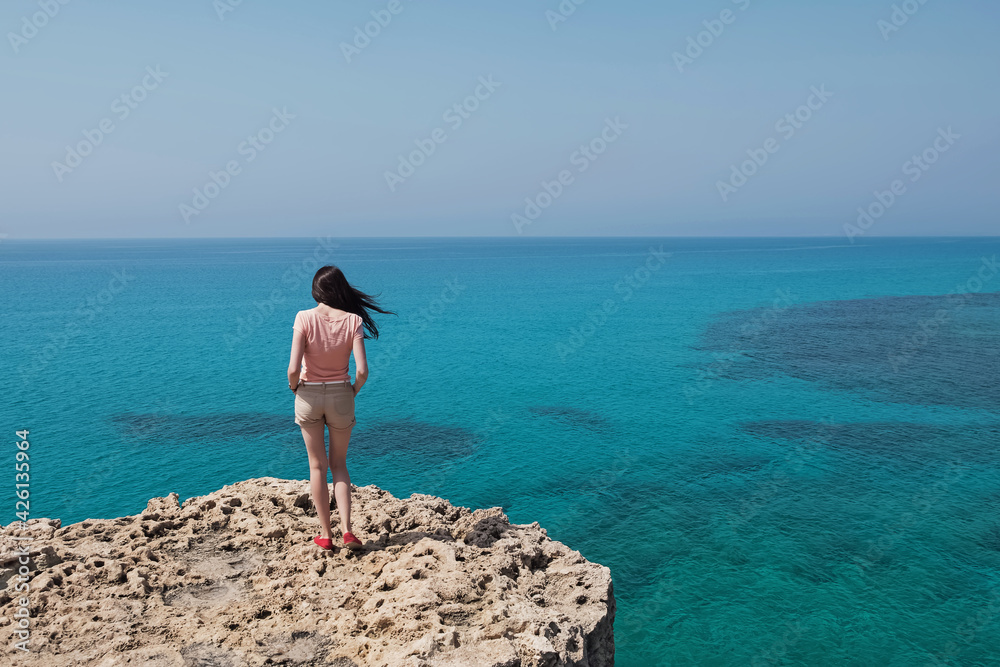 Young woman standing on the cliff with beautiful view t