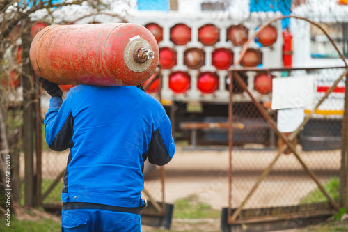 Obraz na płótnie A male industrial worker walks with a gas cylinder to a gas car