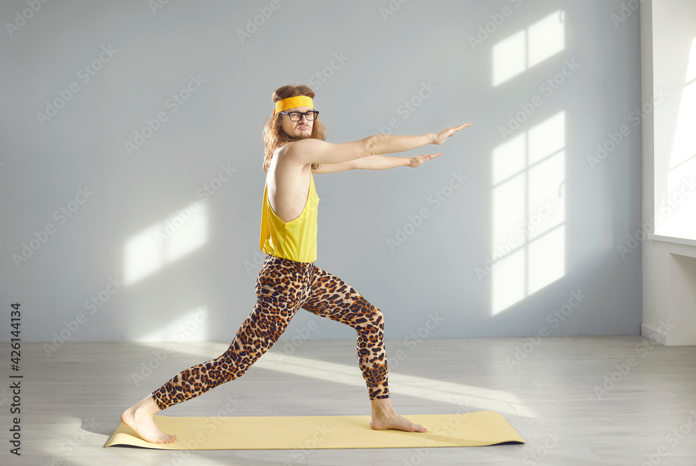 Side view of funny skinny young nerd guy in yellow sweatband and hilarious  leopard leggings doing