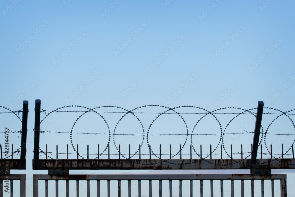 Prison security fence with Barbed Wire against Blue Sky. Crime, Criminals or Terrorists concept. Prison security fence with Barbed Wire against Blue Sky. Crime, Criminals or Terrorists concept.