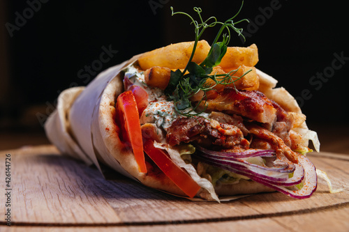 Greek gyros wrapped in pita breads on a wooden board