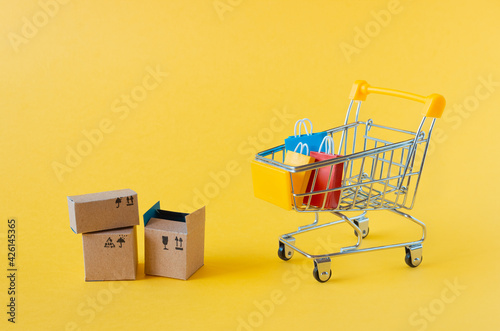 A small grocery cart with boxes and bags on a yellow background.