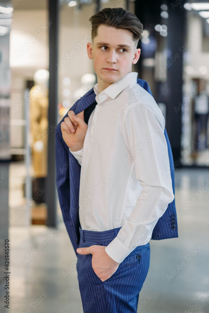Fototapeta premium young business man holds a jacket on his shoulder and looks to the side with hand in his pocket