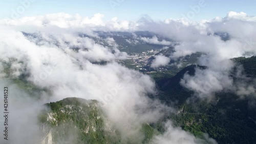 Aerial flight over mystic clouds and Monts Jura in Jura department,France. Beautiful sunny day and Saint-Claude city in the valley. photo