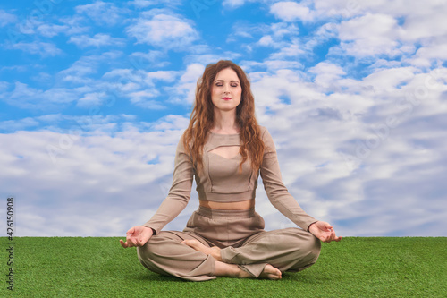 young woman sitting in meditation pose on heavenly background