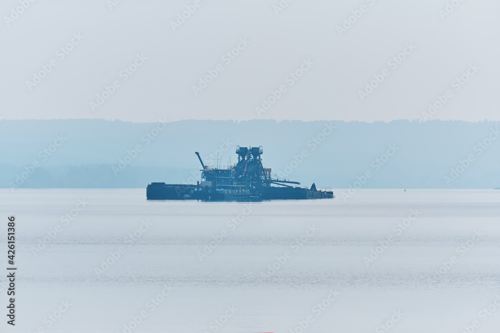 floating sand mining plant on the river in the morning fog
