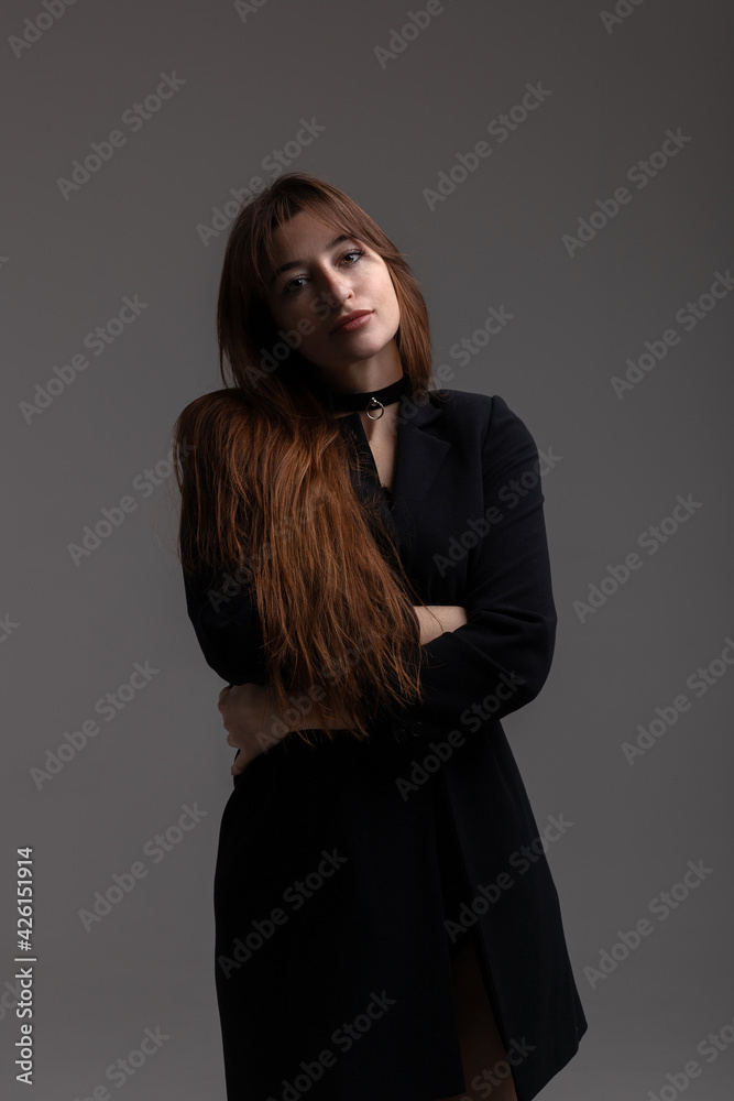 Portrait of young model in total black posing on grey background in studio Portrait of young model in total black posing on grey background in studio