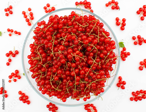 A large bowl of red currants with juicy bunches scattered around.