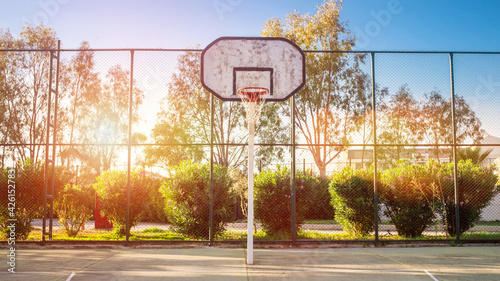 Empty basketball court with high backboard behind metal fence photo