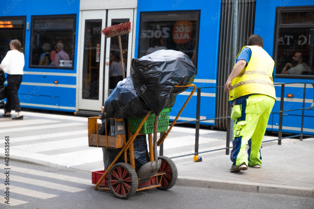 Stockholm, Sweden - June 7, 2019: Street worker in special uniform cleans the city street with tool pliers