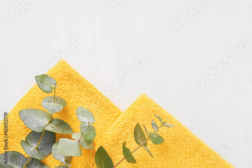 Folded yellow towels and green eucalyptus branches on a white background. SPA concept