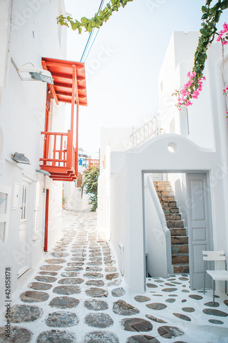 The narrow streets of the island with blue balconies, stairs and flowers in Greece.