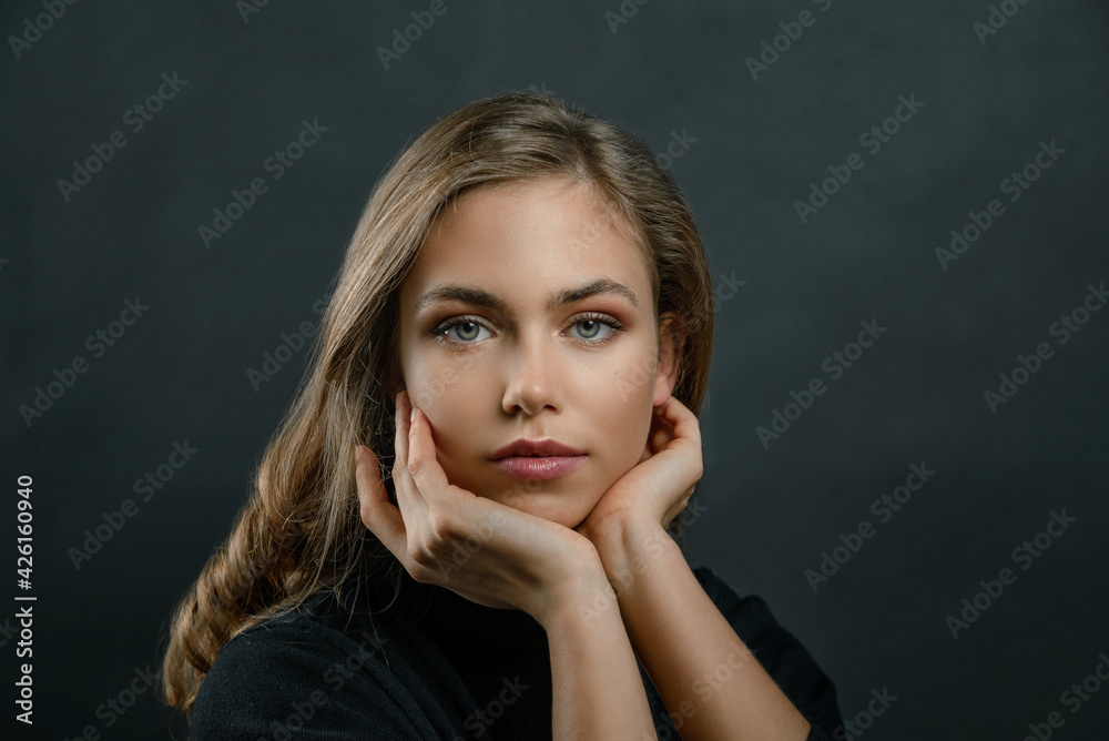 Fototapeta premium beautiful young blonde girl close up in black clothes on a black background. portrait of a beautiful elegant woman