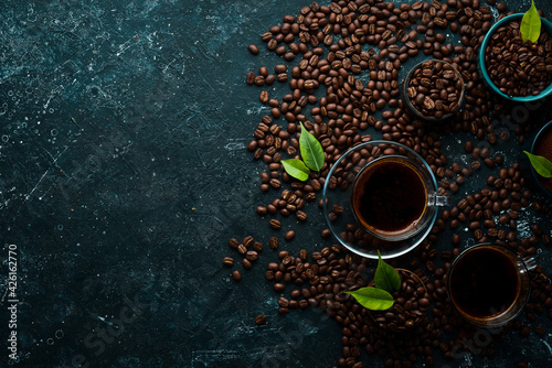 Two cups of fragrant coffee and coffee beans on a black stone background. Top view. Free space for text.