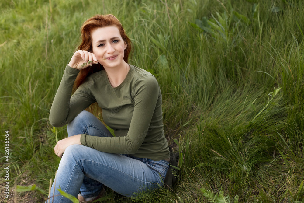 Redhead girl in green grass. Nature. Portrait of a girl Redhead girl in green grass. Nature. Portrait of a girl