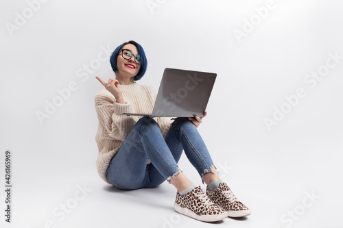 A woman sitting on the floor and holding a laptop