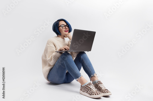 A woman sitting on the floor and holding a laptop