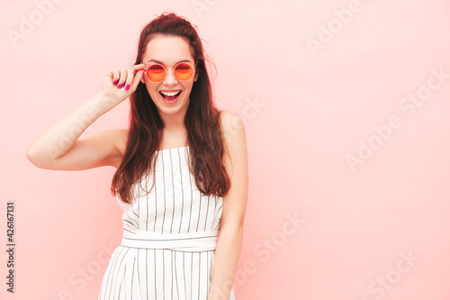 Portrait of young beautiful smiling female in trendy summer hipster overalls clothes. Sexy carefree woman posing near pink wall in studio. Positive model having fun indoors. Cheerful and happy © halayalex