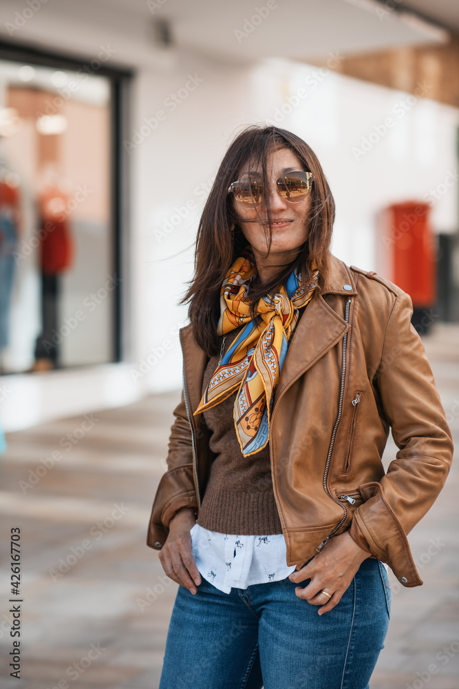 An Asian woman in a leather coat and jeans walking around Europe city