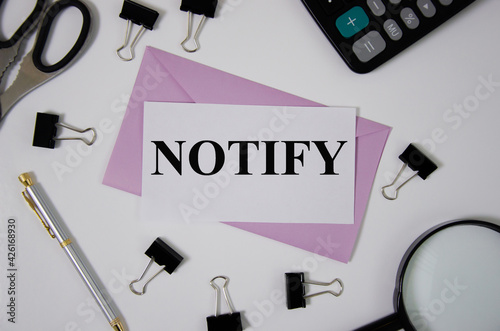notify word written on pink envelope near office supplies