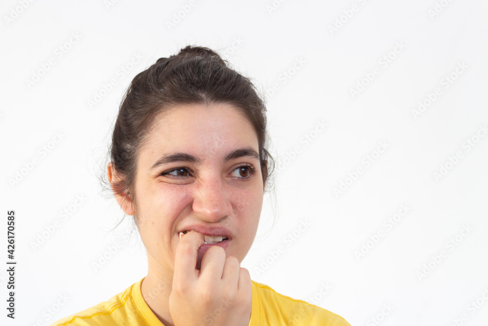 Woman with yellow t-shirt on white background biting her nails Woman with yellow t-shirt on white background biting her nails