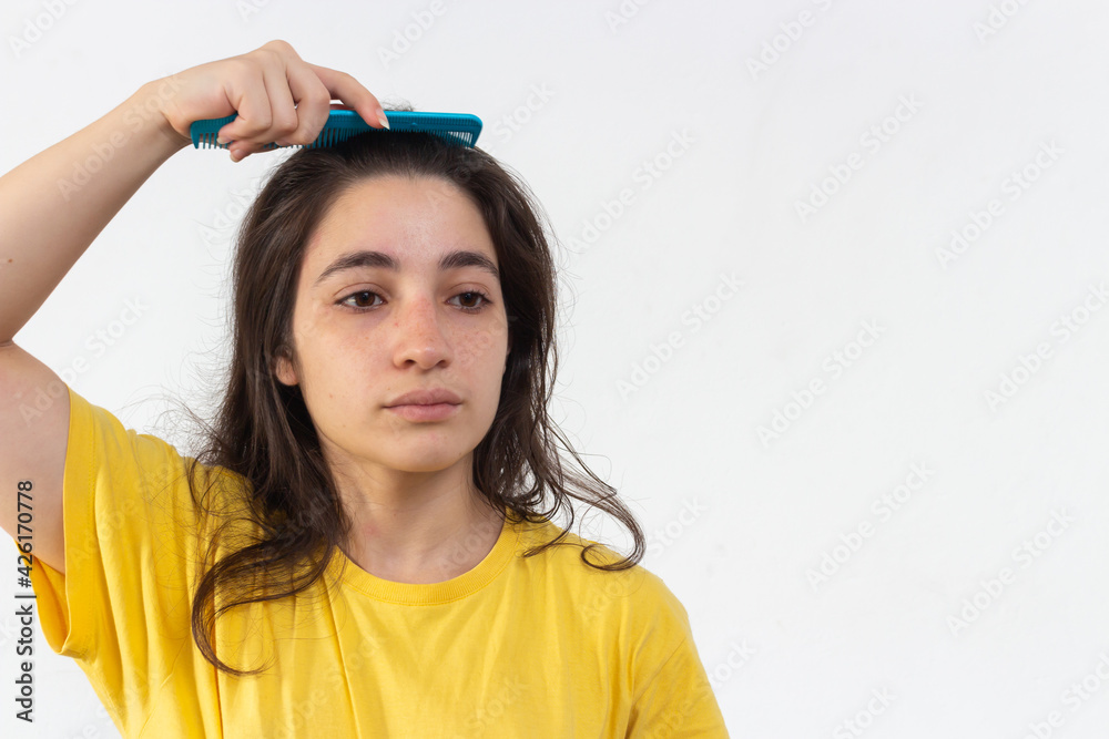 Woman with yellow t-shirt on white background combing her hair Woman with yellow t-shirt on white background combing her hair