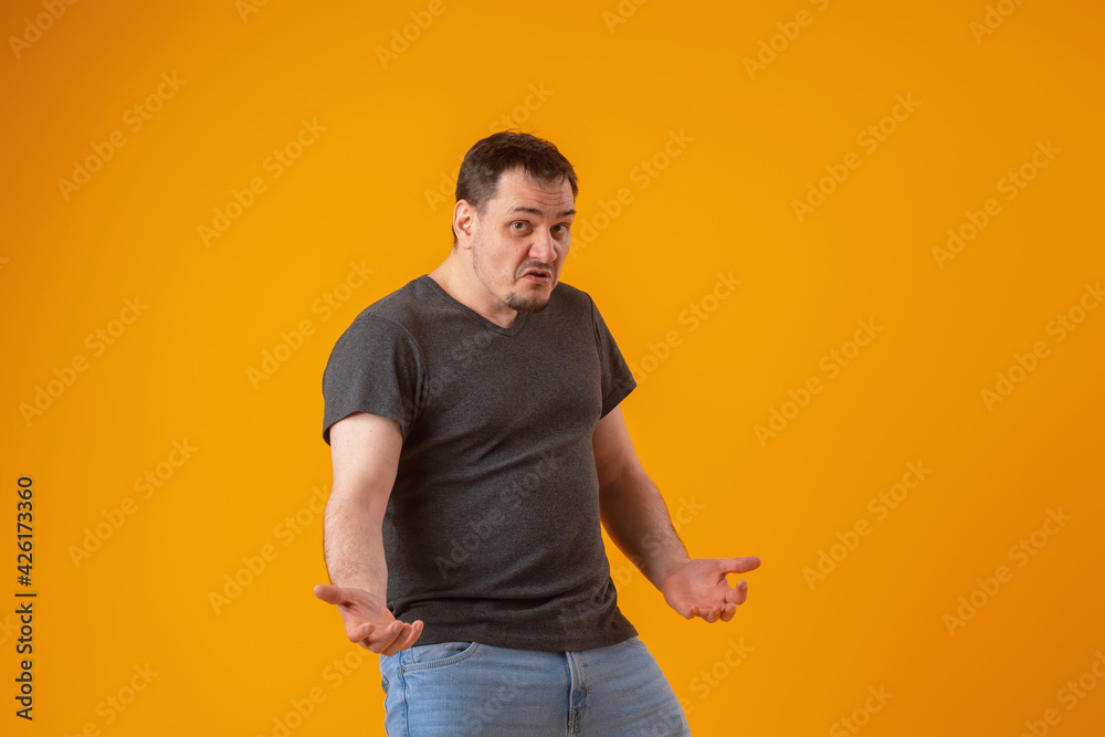 An angry inadequate violent emotionally unstable person with a dissatisfied expression gestures with his hands on a yellow background in the studio. Aggressive behavior An angry inadequate violent emotionally unstable person with a dissatisfied expression gestures with his hands on a yellow background in the studio. Aggressive behavior