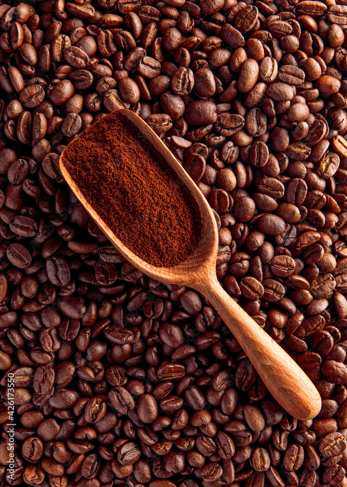 Fototapeta premium Wood scoop with ground coffee on beans background