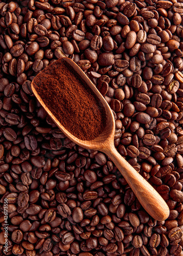 Wood scoop with ground coffee on beans background