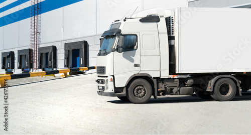 Loading dock of large warehouse with white truck under loading