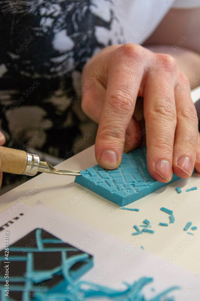 Obraz premium hands of the artist carving patterns into rubber.