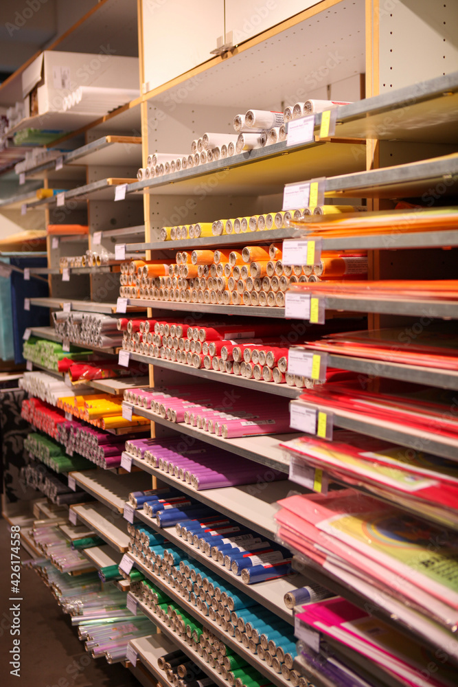 Fototapeta premium Coloured paper rolls and a sheet of paper on shelves.