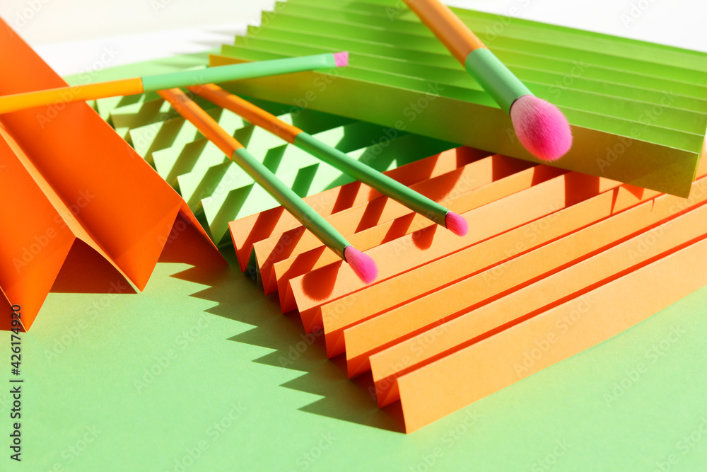 Set of fashion makeup brushes with harsh shadow of sun on green background. Creative cosmetic or beauty concept. Selective focus. Close-up. Set of fashion makeup brushes with harsh shadow of sun on green background. Creative cosmetic or beauty concept. Selective focus. Close-up.