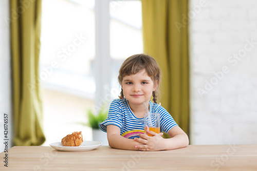 the child girl has breakfast in the kitchen at home.